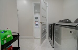 A laundry room with a washing machine, a dryer, and a cart with cleaning supplies. - Central Convenience x Modern Luxury - Heart of Houston (Houston)