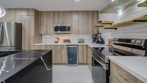 A modern kitchen with stainless steel appliances, wooden cabinets, and a black marble countertop. - Central Convenience x Modern Luxury - Heart of Houston (Houston)