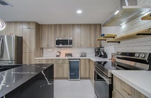 A modern kitchen with stainless steel appliances, wooden cabinets, and a black marble countertop. - Central Convenience x Modern Luxury - Heart of Houston (Houston)