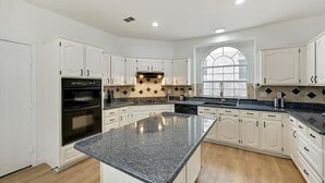 Una cocina moderna con armarios blancos, encimera de granito y una isla grande.
