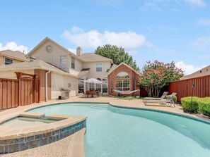 Un jardin avec une piscine, un patio couvert et une construction en briques.