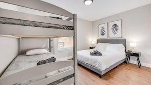 A modern bedroom with a bunk bed, a single bed, and a nightstand with a lamp. - Boho Chic Home w Backyard Paradise - Pool + Grill (North Richland Hills)