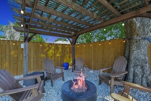 Ein überdachter Außenbereich mit Adirondack-Stühlen, einer Feuerstelle und einer Holz-Pergola.