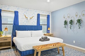 Ein Hotelzimmer mit einem Bett, einem Nachttisch aus Holz, einer Wandpflanze und einem gemusterten Teppich.