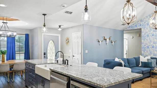 Una cocina moderna con una isla central, iluminación colgante y una pared azul de acento.