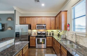 A modern kitchen with wooden cabinets, stainless steel appliances, granite countertops, and a window with blinds. - Chic & Central 3-bd Townhouse, Mins to DT (Houston)