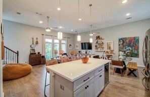 Eine geräumige Küche mit Kochinsel, Pendelleuchten und einem Essbereich mit Stühlen und Tisch.