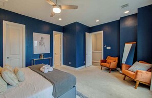 Ein Schlafzimmer mit einem Bett, einem Sessel, einer Couch, einem Deckenventilator und einem Bild an der Wand.