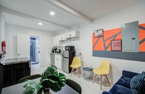 Ein moderner Wohnraum mit Essbereich, Küche und einem blauen Sofa.