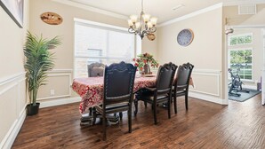 A dining room with a wooden table and chairs, a chandelier, and a clock on the wall. - 5bd, 4BA Entertainment Hub - Playground, Cinema, Gym (Frisco)