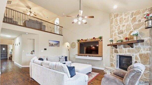 A spacious living room with a stone fireplace, a large flat-screen TV, a ceiling fan, and a staircase leading to an upper level. - 5bd, 4BA Entertainment Hub - Playground, Cinema, Gym (Frisco)