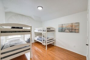 A room with bunk beds, a painting of a beach, and a white ceiling fan. - Texan 5/3 Oasis - Hot Tub, Pool, Cinema Room (Rowlett)