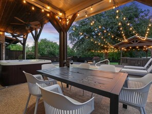 Eine Terrassengruppe mit Tisch, Stühlen, Lichterkette und Whirlpool.