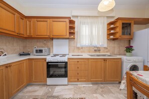Eine Küche mit Holzausstattung, einer Mikrowelle, einem Herd, einem Backofen, einer Spüle und einer Waschmaschine.