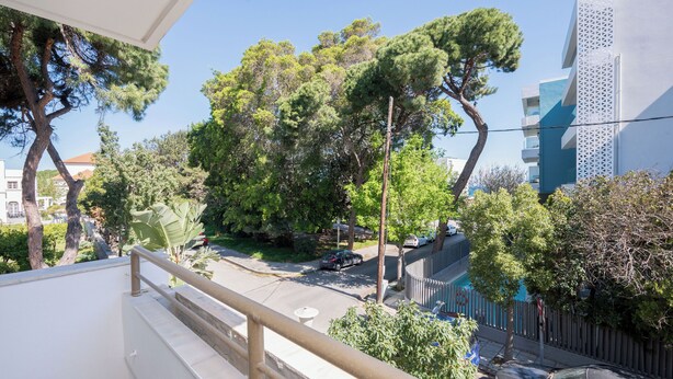 A balcony with a railing overlooking a street with cars and trees. - Stylish and comfortable apartment 2 minutes from the beach (Kos)