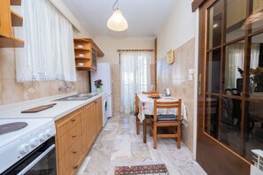 Eine Küche mit Herd, Spüle, Holzschränken und einem Essbereich mit Tisch und Stühlen.