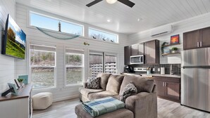 A modern kitchen with a dining area, large windows, and a ceiling fan. - Dock Holiday - Unique Floating House on Cumberland (Russell Springs)