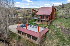 A large house with a red roof, stone walls, and a balcony with outdoor seating. - 1‑Acre Steamboat Escape: Decks, Hot Tub & Minutes to the Slopes (Steamboat Springs)
