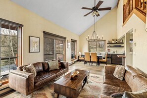 A spacious living room with a brown leather sofa, a wooden coffee table, and a chandelier. - 1‑Acre Steamboat Escape: Decks, Hot Tub & Minutes to the Slopes (Steamboat Springs)
