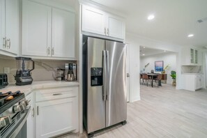 A modern kitchen with white cabinets, a stainless steel refrigerator, a coffee maker, and a blender. - Bright and Spacious Home for w Pool -over 30 Nights- (Houston)