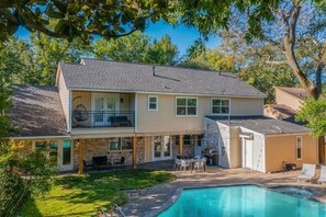 Ein zweistöckiges Haus mit Garten, Pool, überdachter Terrasse und Grillplatz.