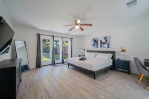 A bedroom with a bed, a desk, a chair, a ceiling fan, and a window with curtains. - Bright and Spacious Home for w Pool -over 30 Nights- (Houston)