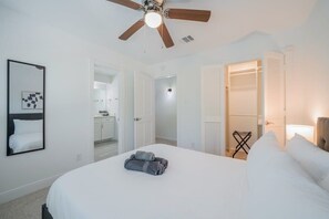 Ein Hotelzimmer mit Bett, Deckenventilator, begehbarem Kleiderschrank und sichtbarem Badezimmer durch eine geöffnete Tür.