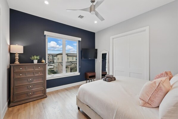 A bedroom with a bed, dresser, TV, and window with a city view. - Luxury Living at its Finest 3bd/3.5ba (Flower Mound)