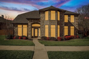 A two-story house with a stone facade, large windows, and a front entrance. - 5BD Glamorous Home Backyward Oasis, Cinema Room (McKinney)