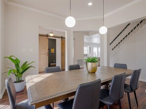 A dining area with a large wooden table, black chairs, pendant lights, and a potted plant. - 5BD Glamorous Home Backyward Oasis, Cinema Room (McKinney)