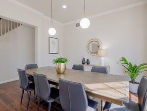 A dining area with a wooden table, six chairs, a potted plant, a round mirror, and pendant lights. - 5BD Glamorous Home Backyward Oasis, Cinema Room (McKinney)