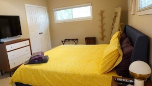 A bedroom with a bed, a TV, a dresser, a window, and a bedside table with a lamp. - Spacious Luxurious House, Big Groups and Pool (Irving)