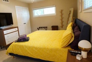 A bedroom with a bed, a TV, a dresser, a window, and a bedside table with a lamp. - Spacious Luxurious House, Big Groups and Pool (Irving)