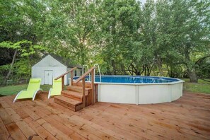 A wooden deck with a swimming pool, a small shed, and two yellow lounge chairs. - Spacious Luxurious House, Big Groups and Pool (Irving)