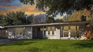 A modern single-story house with a covered porch, large windows, and a well-maintained lawn. - Spacious Luxurious House, Big Groups and Pool (Irving)