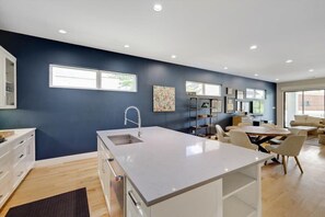 Uma cozinha moderna com ilha central, armários brancos e uma parede decorada em azul escuro.