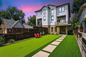 A modern two-story house with a well-maintained lawn, a wooden fence, and a red chair. - Modern Luxury Townhouse Uptown & Attractions (Dallas)