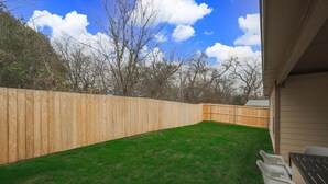 A backyard with a wooden fence, a grassy lawn, and a table with chairs. - Your Vibrant Dallas Getaway Home (Dallas)