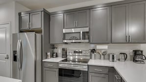 A modern kitchen with grey cabinets, stainless steel appliances, and a white countertop. - Your Vibrant Dallas Getaway Home (Dallas)
