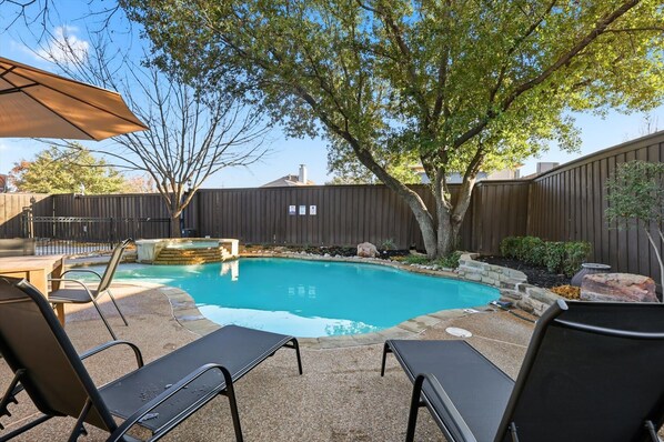 A backyard with a swimming pool, lounge chairs, and a wooden fence. - Luxury Backyard Pool & Patio Oasis (Lewisville)