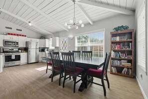 A modern kitchen with white cabinetry, a dining table with chairs, a ceiling fan, and a bookshelf with books. - Charming 3-bed/2-bath Hidden Gem w Yard (Richardson)