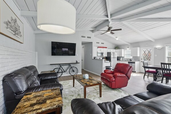 A modern living room with a sofa, a red chair, a coffee table, a television, and a bicycle. - Charming 3-bed/2-bath Hidden Gem w Yard (Richardson)