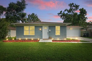 A two-story house with a front porch, a garage, and a well-maintained lawn. - Charming 3-bed/2-bath Hidden Gem w Yard (Richardson)