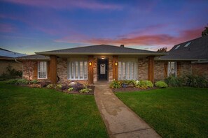A two-story house with a front porch, a brick facade, and a well-maintained lawn. - Best of Richardson 5bd/3ba With Pool, Patio, BBQ (Richardson)