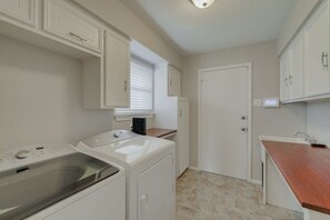 A laundry room with a washing machine, dryer, and a door leading to another room. - Best of Richardson 5bd/3ba With Pool, Patio, BBQ (Richardson)