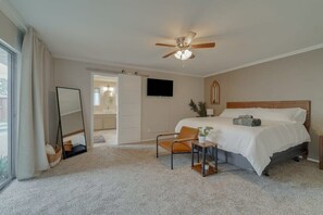 A bedroom with a bed, a chair, a small table, a ceiling fan, a TV, and a mirror. - Best of Richardson 5bd/3ba With Pool, Patio, BBQ (Richardson)