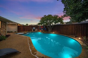 A backyard with a swimming pool, a wooden fence, and a stone pathway. - Best of Richardson 5bd/3ba With Pool, Patio, BBQ (Richardson)