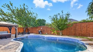 A backyard with a swimming pool, a wooden fence, and a patio area with outdoor furniture. - 5-bd/2-ba Vacation Retreat w/ Pool, Hot Tub & bbq (Fort Worth)