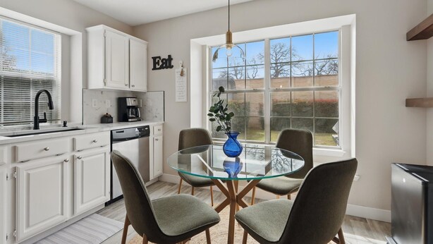 A modern kitchen with white cabinets, a glass dining table, and a view of the outdoors. - 4-bd/2.5-ba Tropical Pool Oasis With a Game Room (Flower Mound)