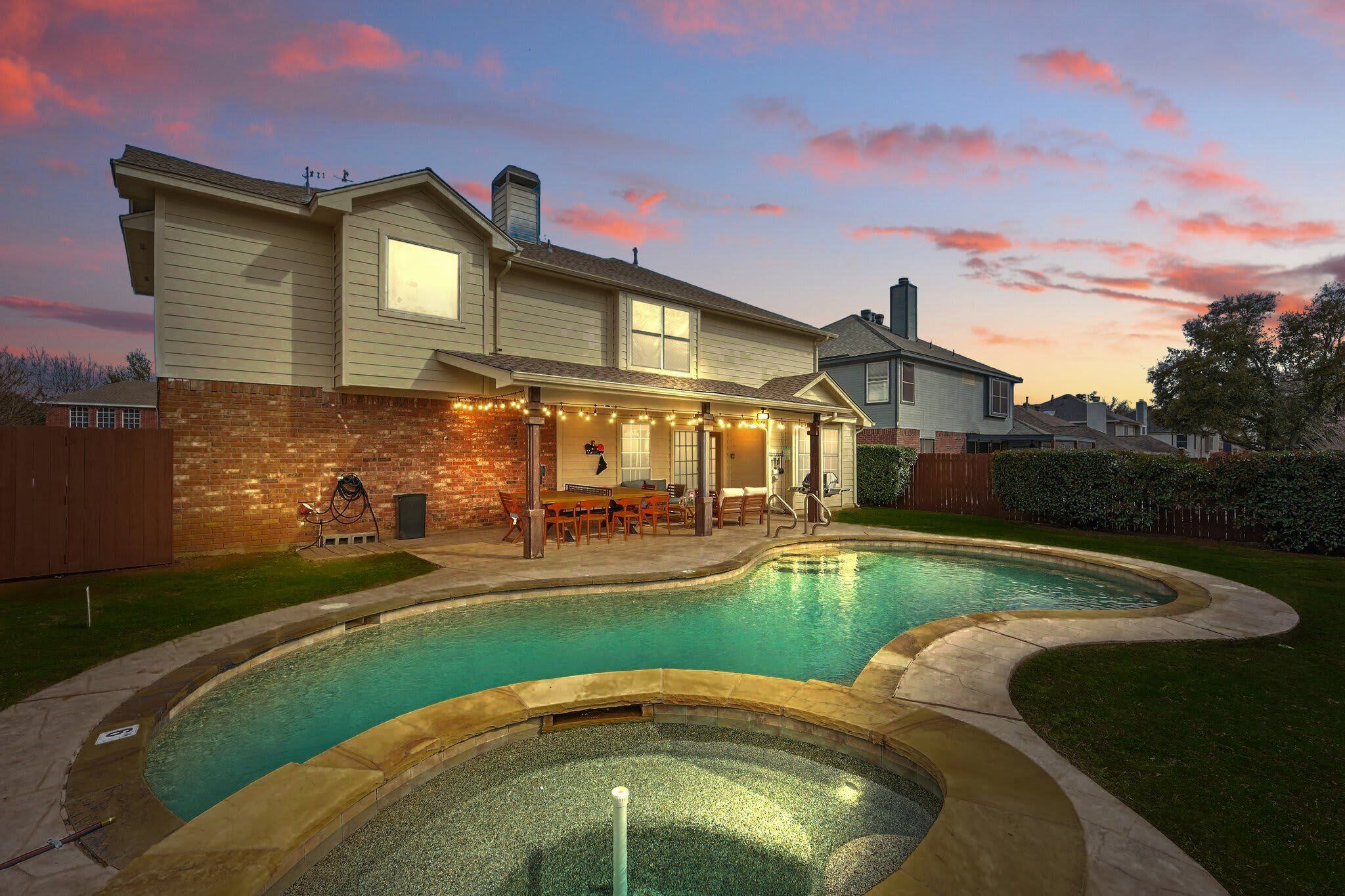 A house with a swimming pool, a covered patio, and a brick exterior.